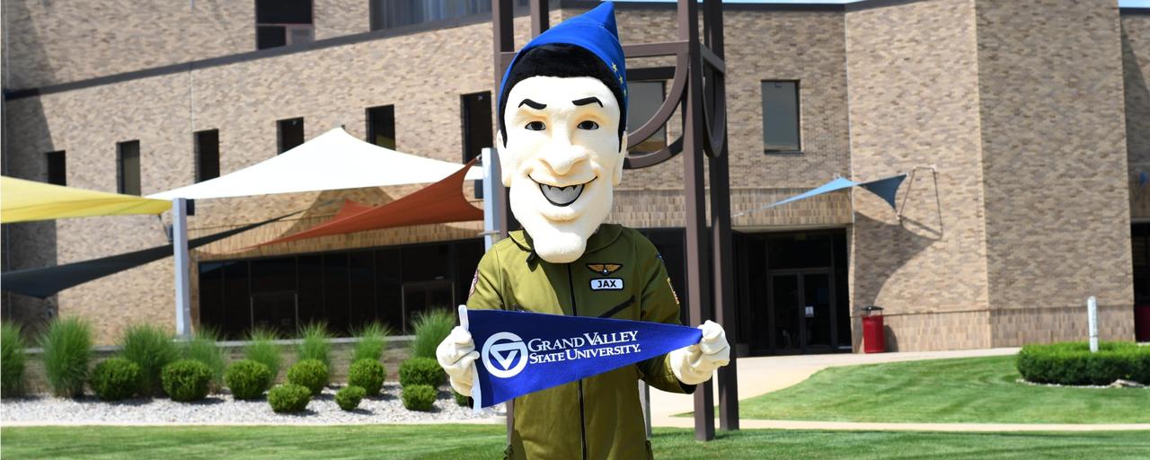 Jax mascot holding GVSU flag in front of Jackson College clock tower